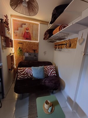 Una habitación acogedora con sofá, una mesita y un estante en la pared con objetos.