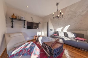 Una habitación moderna con sofá, cama, televisor, lámpara de araña y pared con diseño.