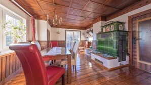 Una habitación con paneles de madera, una mesa de comedor, sillas, un banco y un armario con azulejos verdes.