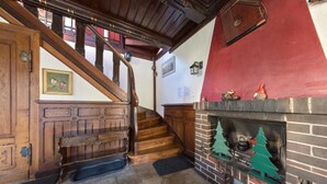 Una escalera de madera que lleva a una plataforma con una chimenea, una pared roja y un cuadro enmarcado en la pared.