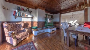 Una sala de estar con piso de madera, un sofá estampado, una mesa de comedor y una estantería.