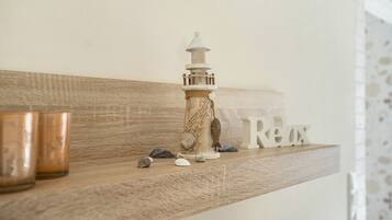 Ein Holzregal mit einem Leuchtturmmodell, Muscheln und einem Schild mit der Aufschrift 'Relax'.