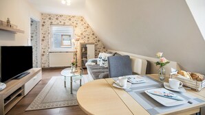 Un salón acogedor con televisor, sofá, mesa de comedor y una pequeña mesa de centro.