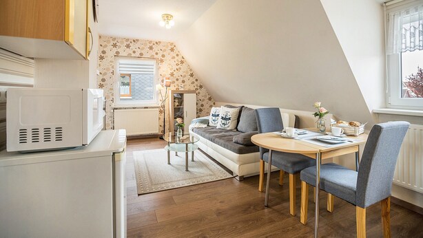 Un espacio habitable compacto con kitchenette, comedor y sofá.