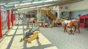 Ein Kinderspielbereich mit Rutschen, Klettergerüsten und einem Sandkasten.
