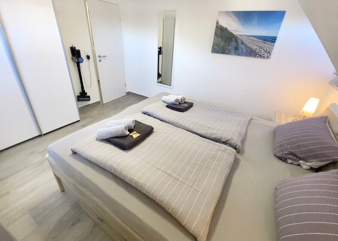 Ein Hotelzimmer mit zwei Betten, einem Spiegel, einem Gemälde und einem Staubsauger.
