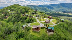 An aerial view of a mountain lodge with multiple buildings, surrounded by lush greenery and mountains in the background. - A Cloud 9 - Mountain Views, Hot Tub Bliss & Pool Table Fun! (Sevierville)