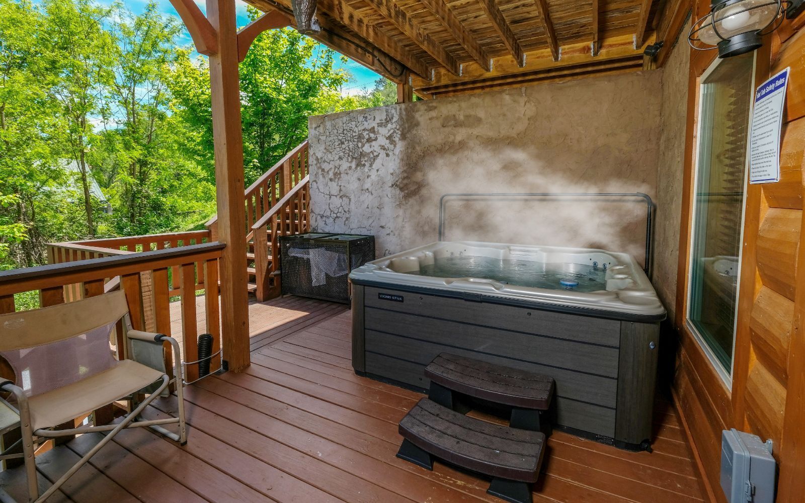 Un jacuzzi en una terraza de madera con barandilla y un banco.