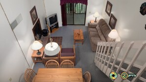 Ein gemütliches Wohnzimmer mit einer Couch, einem Couchtisch, einem Fernseher und einem Essbereich mit Stühlen und einem Tisch.