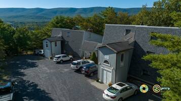 A residential area with multiple houses, a parking lot, and a mountainous backdrop.