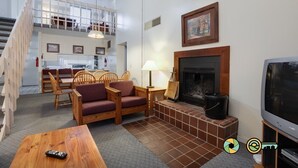 Ein Wohnzimmer mit Kamin, Fernseher und Essbereich mit Stühlen und Tisch.