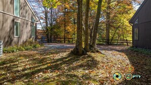 A rustic wooden building with large windows, surrounded by a natural landscape with trees and a wooden fence. - Woodland Retreat (#97B) | Quiet area | Minutes to Bryce Resort! (Basye)