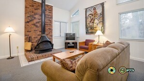 A living room with a fireplace, a television, and a large tapestry. - Woodland Retreat (#97B) | Quiet area | Minutes to Bryce Resort! (Basye)