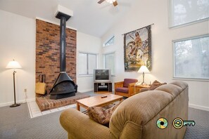 Cozy living area with a fireplace, sofa, armchairs, flat-screen TV, and coffee table.