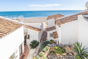 A coastal building with terracotta roofs, a stone pathway, and a view of the sea.