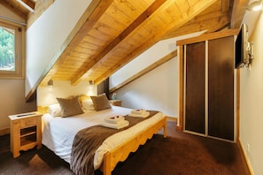 A bedroom with a wooden ceiling, a bed with pillows and a blanket, a nightstand, and a wardrobe. - Vallorcine Loriaz 43 ski in / ski out, Vallorcine (Argentiere), France (Vallorcine (Argentiere))