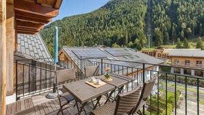 A balcony with a table, chairs, and solar panels.