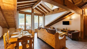 A wooden interior with a dining area, a sofa, and a TV.