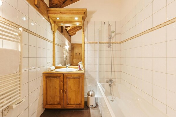 A modern bathroom with a wooden vanity, a large mirror, a bathtub, and a shower area.