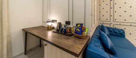 A small kitchenette with a wooden countertop, a kettle, a coffee maker, and a basket of snacks.