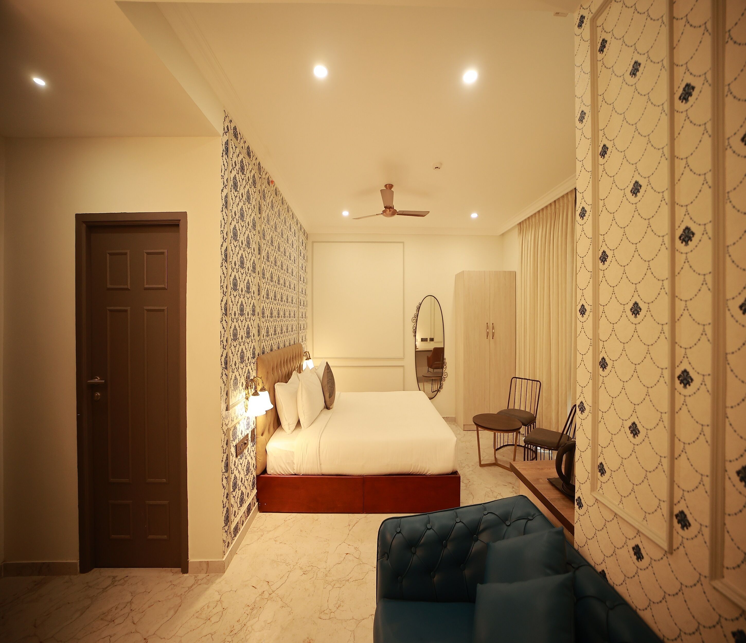Une chambre à coucher comprenant un lit, une table de chevet, une chaise, une armoire et un ventilateur de plafond.