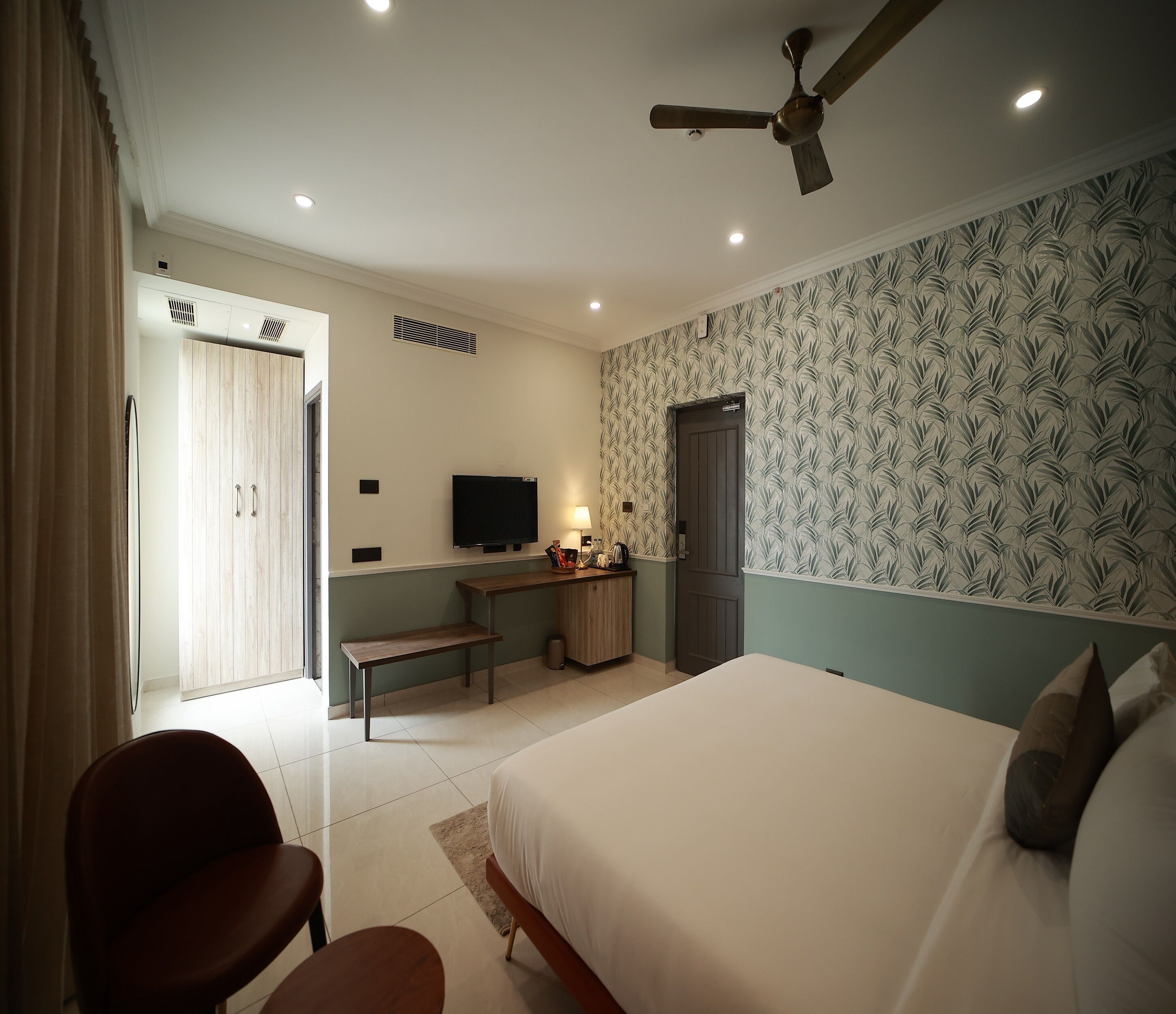 A bedroom with a bed, a desk, a chair, a television, and a wardrobe.