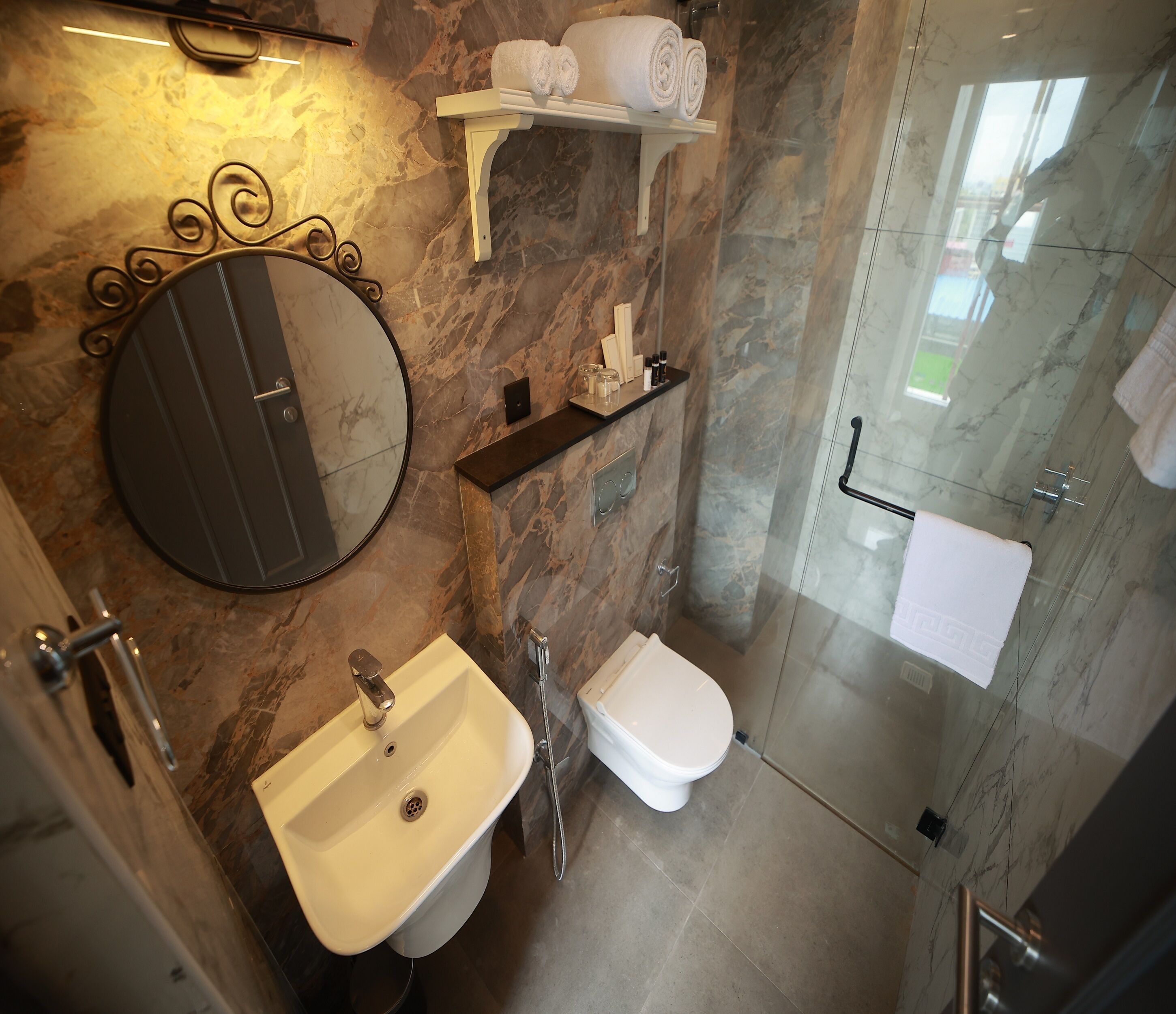 Une salle de bain moderne avec un lavabo en marbre, des toilettes et une douche à parois de verre.