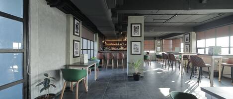 A spacious indoor area with high ceilings, large windows, and multiple seating arrangements.