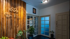 A reception area with a wooden wall, potted plants, and a sign that reads "De Fleur." - De Fleur Hotel (Puducherry)