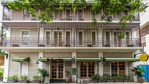 A two-story building with a green awning, multiple balconies with railings, and potted plants. - De Fleur Hotel (Puducherry)