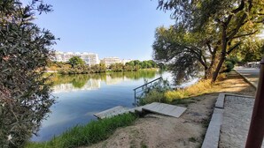 A riverside path with a metal railing, a small wooden platform, and a bicycle in the foreground.