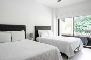 Ein Hotelzimmer mit zwei Betten, einem Deckenventilator, einem Nachttisch und Blick ins Freie.