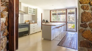 Een moderne keuken met een centraal eiland, barkrukken en een groot raam.