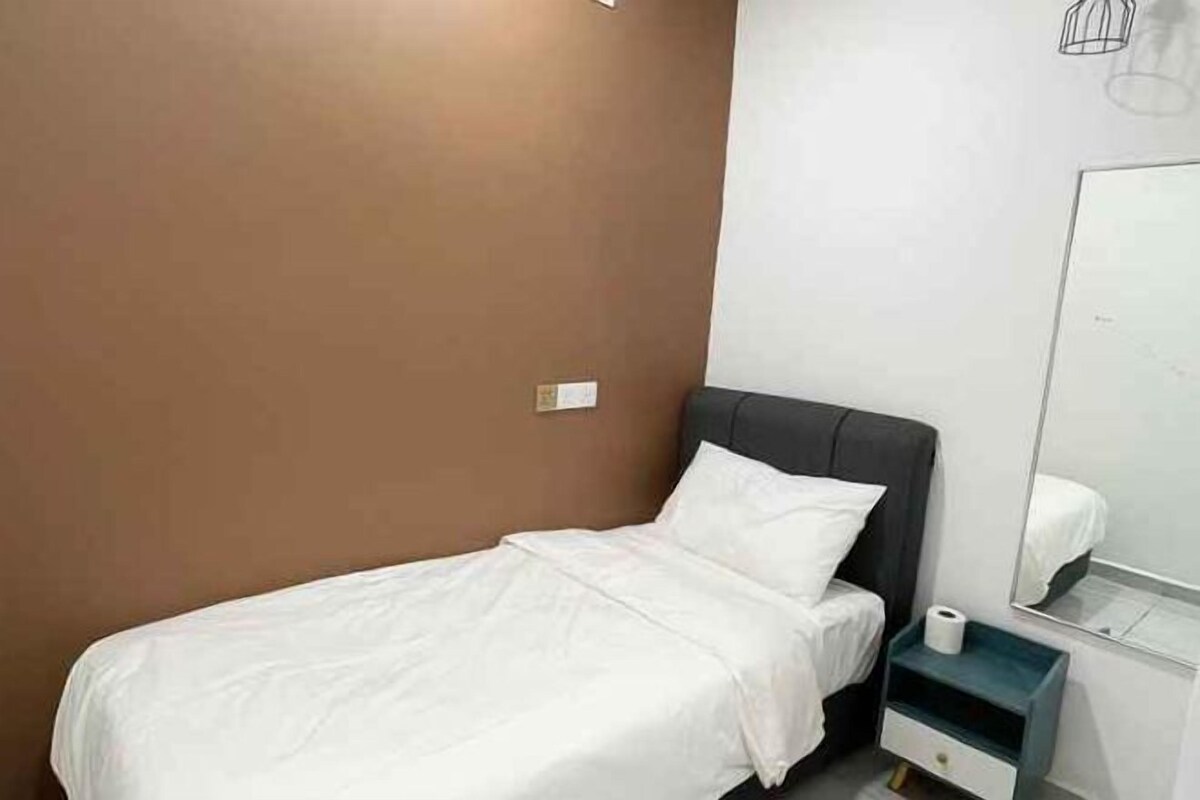 Habitación de hotel con cama, mesita de noche, espejo y enchufe de pared.