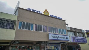 Un immeuble avec une enseigne indiquant « Hôtel Gemilang » et un magasin appelé « TwentyOneMart ».
