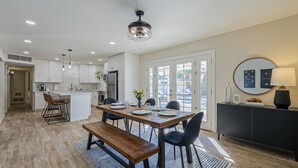 A modern kitchen with white cabinets, a wooden dining table, and a built-in island. - Old Town Retreat • Luxe Pool & Outdoor Space for Relaxing Getaways (Scottsdale)