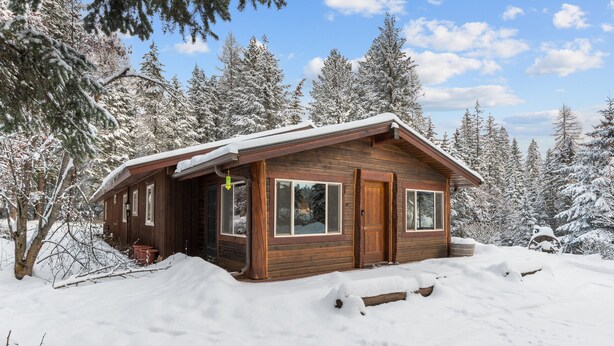 A wooden cabin with a sloped roof, large windows, and a door. - The Lazy Bear - Mountain Retreat with Sauna (Whitefish)