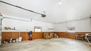A spacious, well-lit garage with concrete floors, wooden walls, and various storage items. - The Lazy Bear - Mountain Retreat with Sauna (Whitefish)