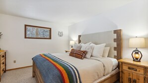 A bedroom with a bed, bedside tables, a lamp, and a window. - The Lazy Bear - Mountain Retreat with Sauna (Whitefish)