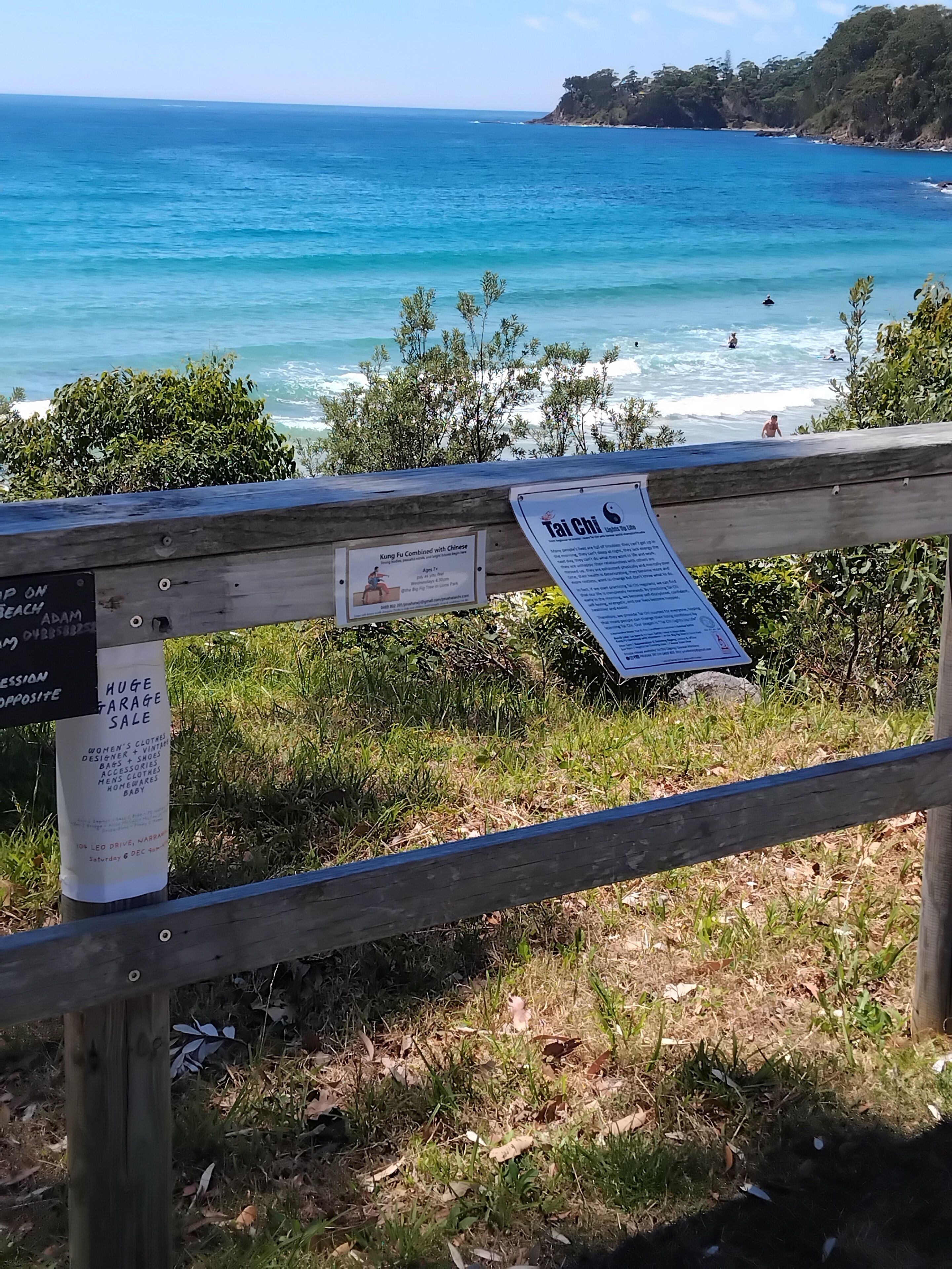 A wooden fence with signs indicating a garage sale and a Tai Chi class.