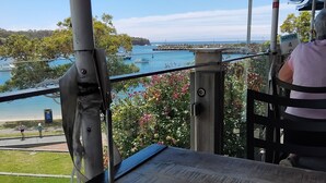 A table with a cup of coffee and a spoon, overlooking a marina with boats and a clear sky. - Beach House in the Ulladulla Mollymook Milton area (Ulladulla)