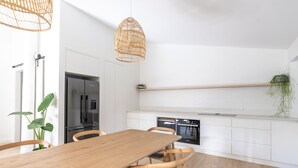 A modern kitchen with white cabinetry, a wooden dining table, and a built-in oven. - Surfside Retreat | Gnarabup (Gnarabup)