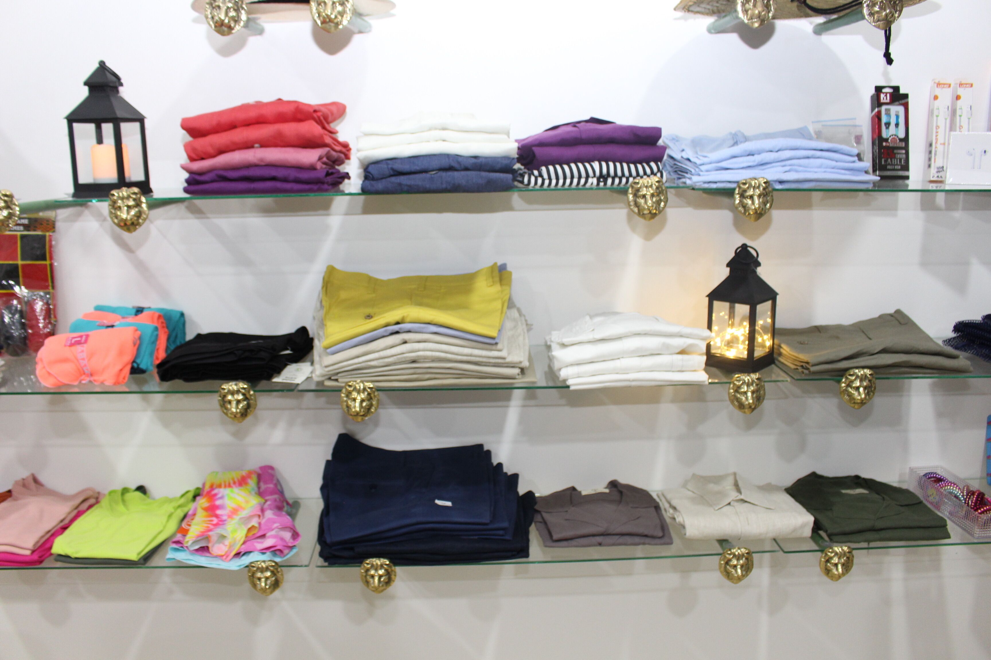 A clothing store with various folded garments on glass shelves.