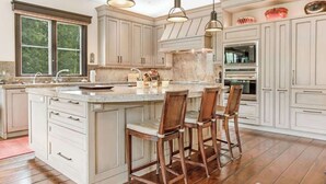 A spacious kitchen with a large island, wooden bar stools, and modern pendant lighting. - Elegant Beaver Creek Retreat (Beaver Creek)