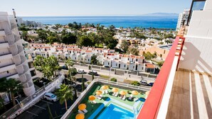 A hotel with a pool, a view of the sea, and a cityscape in the background.