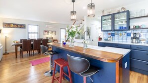 A modern kitchen with a central island, bar stools, and pendant lighting.