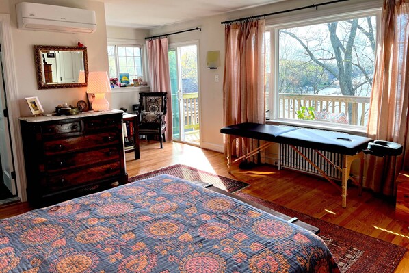 A bedroom with a bed, dresser, desk, and a view of the outdoors.