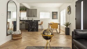 Un vaste espace de vie comprenant une cuisine moderne, une table à manger et un canapé en cuir noir.