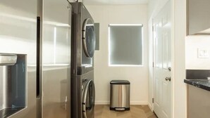 Une cuisine moderne dotée d’appareils électroménagers en acier inoxydable, d’une poubelle et d’une fenêtre avec un panneau en verre dépoli.