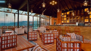 Un restaurant avec des sièges aux motifs originaux, un bar et de grandes fenêtres offrant une vue sur les montagnes.